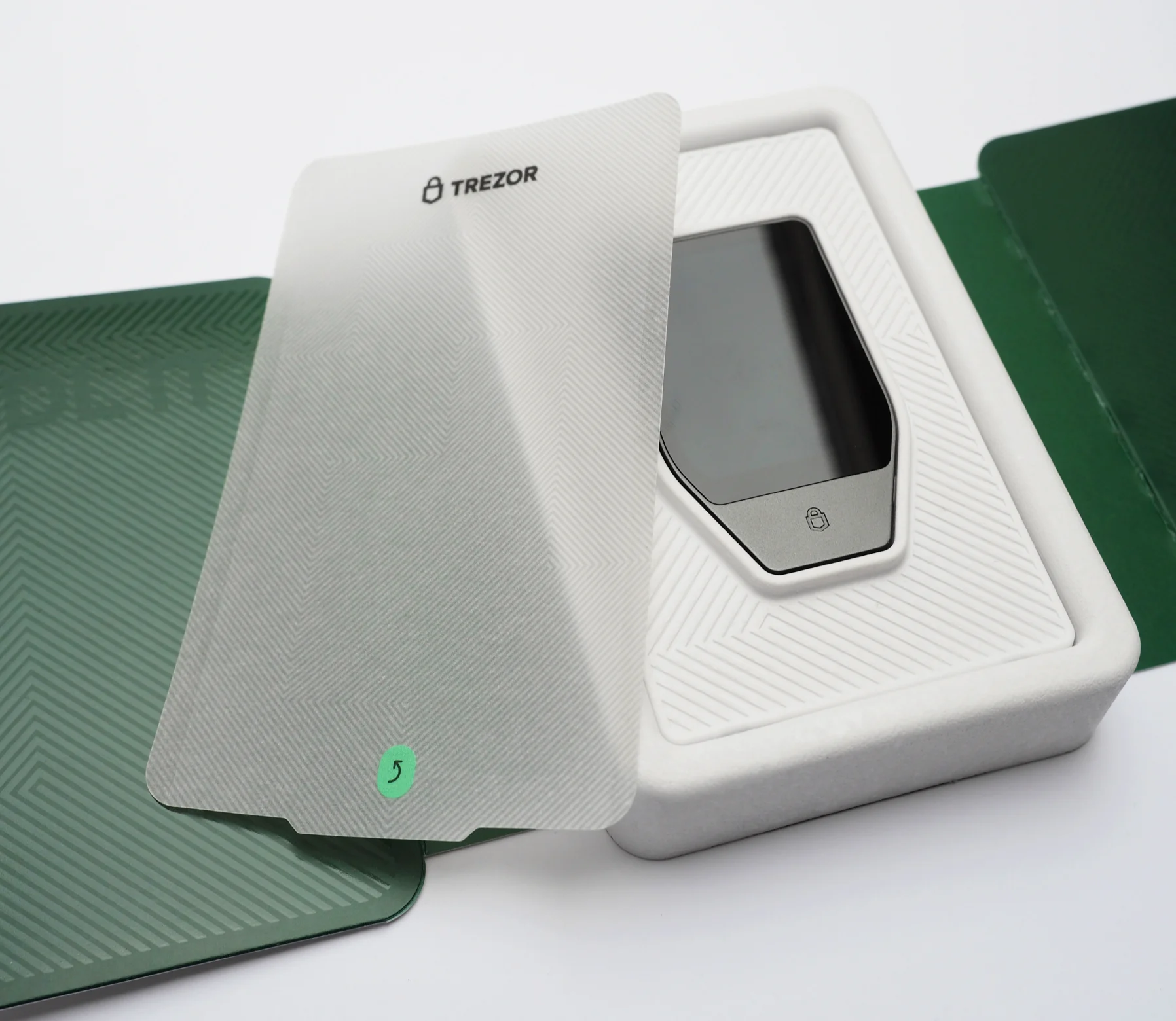 A white privacy screen protector lifted from the tray, revealing the Safe 7 seated in its white cradle.