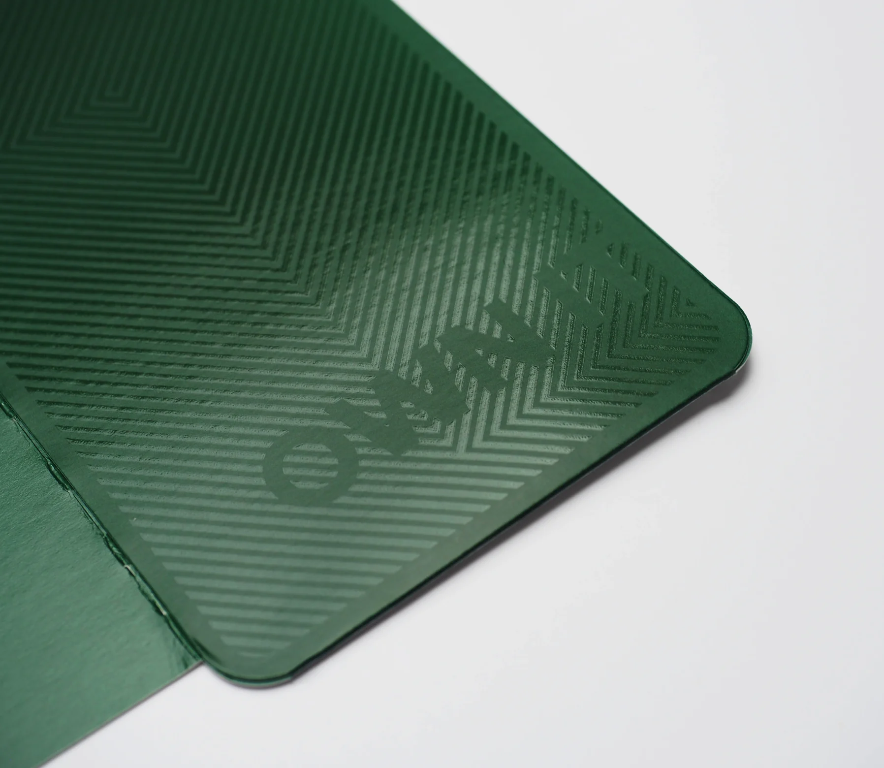 A macro of the dark-green inner panel — herringbone emboss and a raised “Own it” catching the light.