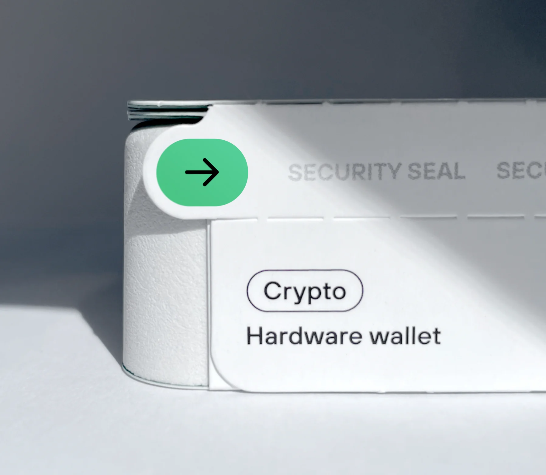 Close-up of white “Crypto hardware wallet” packaging with a green arrow security seal.